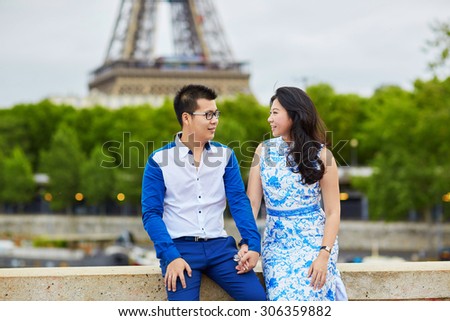 Young romantic Asian couple having a date on the bridge over the Seine near the Eiffel Tower, Paris, France