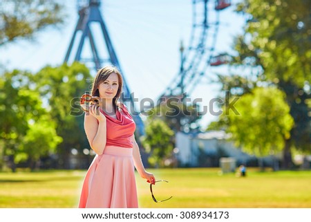 Beautiful young tourist in Prater amusement park of in Vienna, Austria, holding pretzel