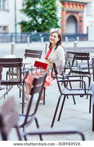 Beautiful young woman in an outdoor cafe writing in a notebook and planning her day in Vienna, Austria
