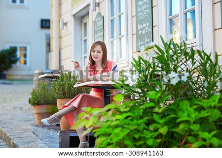 Beautiful young woman in an outdoor cafe using map and planning itinerary in Vienna, Austria