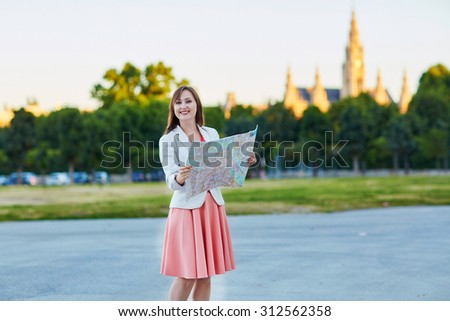 Beautiful young woman walking in Vienna, Austria and using map