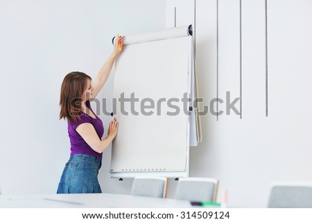 Pretty young student or business woman writing on a paper board during a class or business meeting