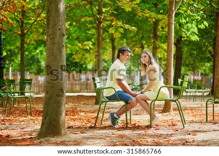 Beautiful young dating couple in Paris in the Tuileries garden on a warm and sunny autumn day