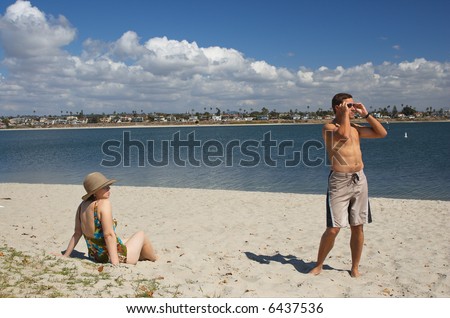 Attractive young couple on the beach looking at an object of interest off camera.