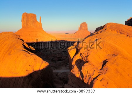 Boulders framing Mittens in Monument Valley, Navajo Nation are lit by setting sun