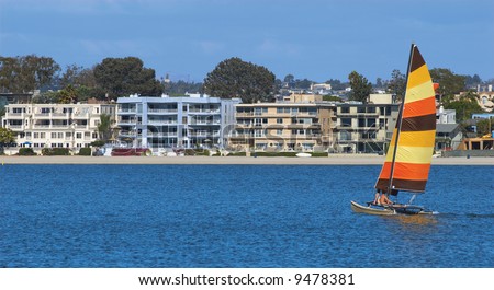 A young couple is sailing towards condominiums in Mission Bay, San Diego, California. A perfect metaphor for sailing to first home ownership through the sea of life.