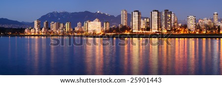 Downtown Vancouver on a winter evening glows in the dusk against a backdrop of majestic mountains