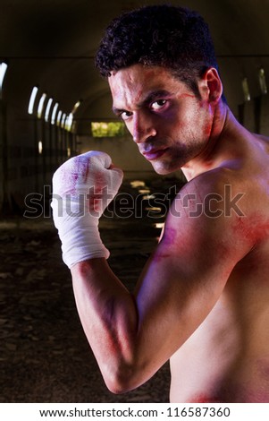 View of a wounded fighter with blood stains on a abandoned factory.