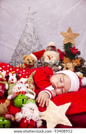 View of a newborn baby on a Christmas suit with stuffed toy.