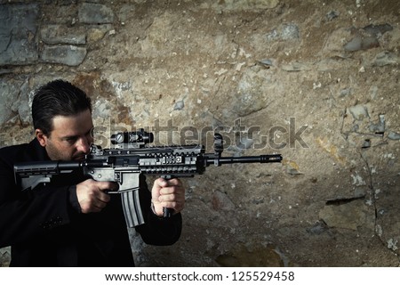 View of a contracted type killer agent wandering with a jacket and machine gun.