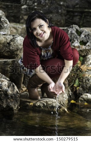 Young beautiful woman playing with water on a pond.
