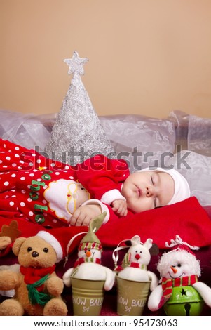 View of a newborn baby on a Christmas suit with stuffed toy.