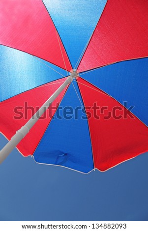 A blue and red beach umbrella from underneath. The symbol of summer.