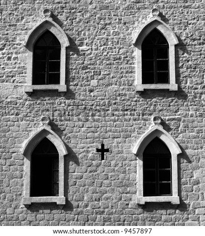 Brick wall with gothic windows and cross. B&W image.