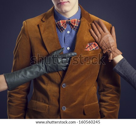 Stylish man in a red suit and women\'s hands in leather gloves.