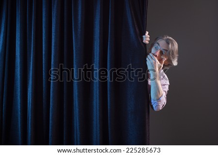 Scared man hiding behind a curtain.