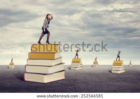 Education. Businesswoman looking into the distance while standing on the foot of books.