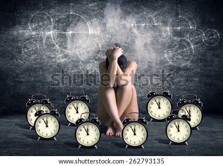 Nude woman sitting head in hands among a large number of watches and alarm clocks.