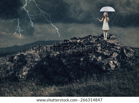 Girl with a white umbrella stands on the top of a mountain during a severe thunderstorm.
