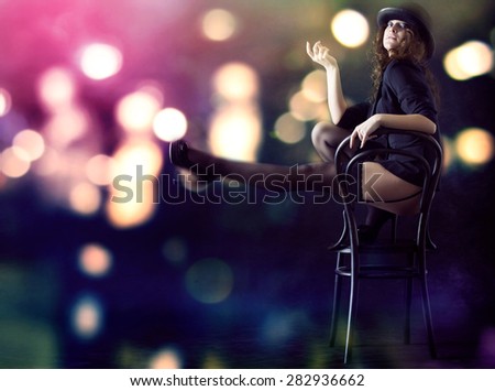 Sexy young woman sitting on a chair against a background of bright lights at night.