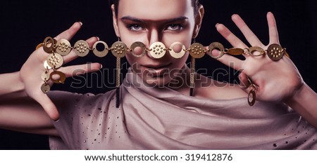 Luxury young woman in a bright makeup with gold jewelry in their hands.