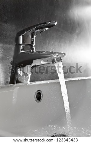 Bathroom sink silhouette lighted by backlight with water splash