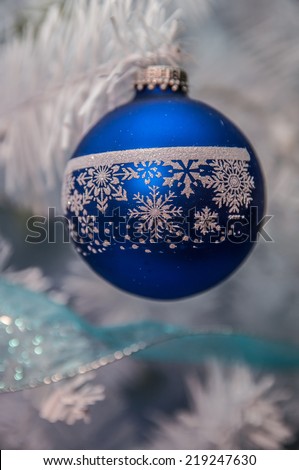 Christmas tree ornaments hanging from branch of a white tree. / Christmas tree ornament on a tree