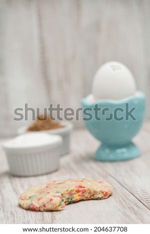 Colorful birthday confetti cookie with a bite taken out with egg and sugars