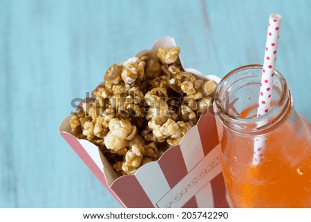 Caramel popcorn in a bag with orange soda pop with straw