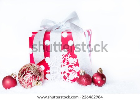 Christmas gift wrapped with silver bow with red ornaments and snow flakes