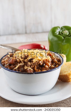 Delicious bowl of warm chili winter comfort food dinner with corn bread muffin red and green peppers vertical