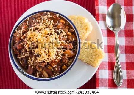 Bowl of warm chili winter comfort food with corn bread muffin and spoon from above