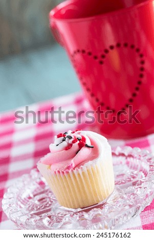 Single Valentines Day cupcake on plate with tin heart bucket