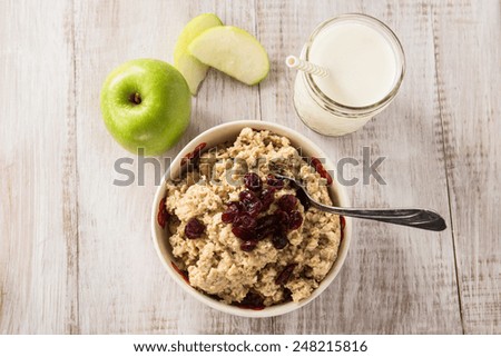 Heart healthy oatmeal breakfast cereal with apples and cranberries and glass of milk