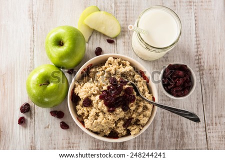 Bowl of heart healthy breakfast oatmeal with apples and cranberries and glass of milk