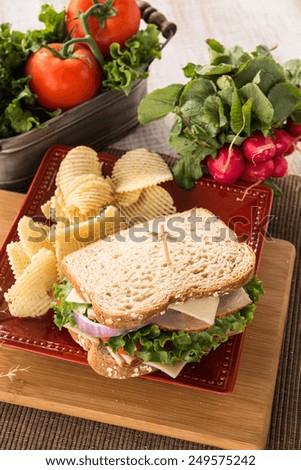 Turkey Ham and Swiss cheese sandwich with potato chips and tomatoes and radishes