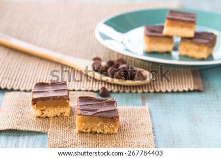 Chocolate and caramel candy cookies Millionaire Bars with wood spoon and chocolate chips