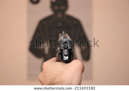 Human hand holding gun and aim at a target