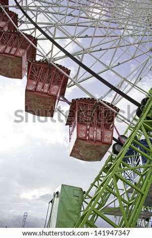 Ferris wheel in amusement park colors with metal booths, fun and party