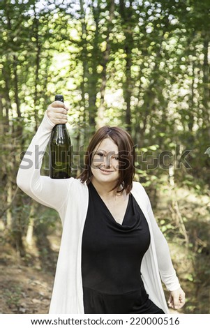 Girl lifting bottle of champagne in park, party