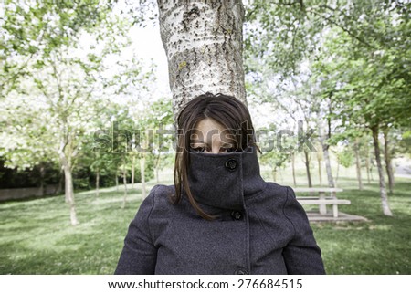 Fearing woman covered with coat in park
