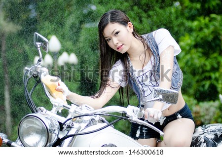 Beautiful girl is washing big bike