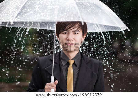 Smart business man holding umbrella among the rain