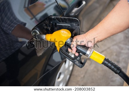 transportation concept - man pumping fuel in car at petrol station