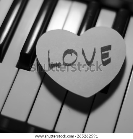 paper heart on piano keyboard black and white color