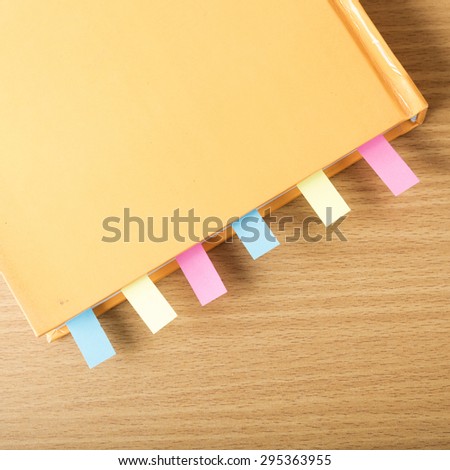 orange book with sticky note on wood background