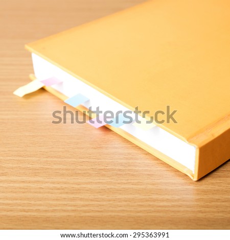 orange book with sticky note on wood background