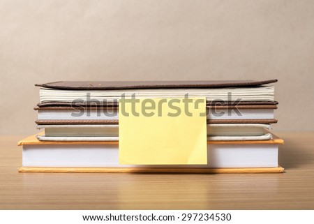stack of book with sticky note on wood background