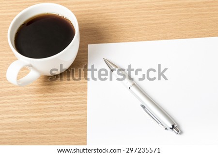 coffee cup with white paper and pen on wood background
