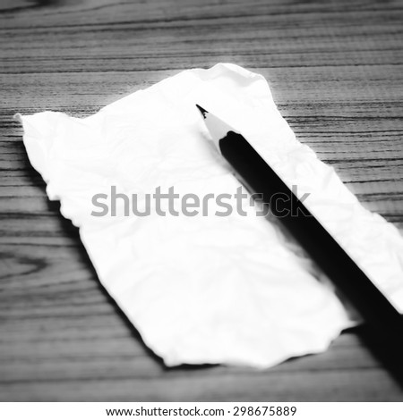 paper scrap with pencil on wood background black and white color tone style